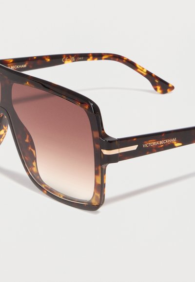 Τετράγωνα γυαλιά ηλίου με καφέ φακούς σε βαθμιαία απόχρωση και σχέδιο επένδυσης σε σχήμα χελώνας, με το λογότυπο "Victoria Beckham" στο πλαϊνό σκελετό.