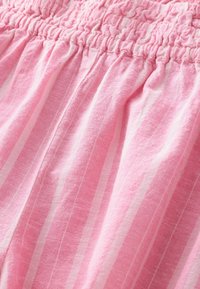 Roze stof met een smocktailleband heeft verticale witte strepen. De textuur lijkt zacht en licht gekreukt.