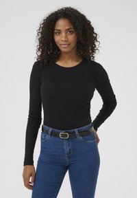 Maglietta nera a maniche lunghe dal design aderente con scollo rotondo. Abbinata a jeans blu a vita alta e una cintura nera con un dettaglio di fibbia dorata.