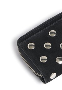 Billetera de ante negro con tachuelas metálicas plateadas, cierre con cremallera y detalles de costura en contraste. Presenta una textura suave y un diseño compacto.
