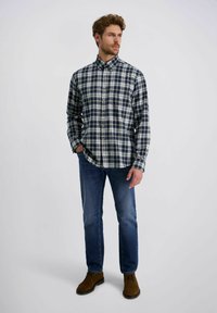Blauw-witte geblokte overhemd met lange mouwen en knoopkraag, gecombineerd met blauwe jeans en bruine suede schoenen. Getextureerde katoen stof.