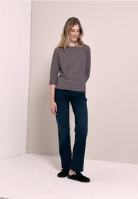 Randig långärmad topp i grått och marinblått, matchad med mörkblå tygbyxor. Svarta slip-on skor. Slät textur, avslappnad passform.