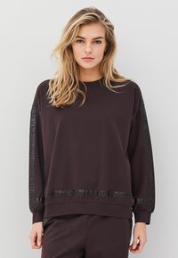 Musthave mustripsiga must nokk, millel on nahataolised aktsendid õlgadel ja servades. Pehme tekstuur ja lahtine lõige, ümar kaelus.