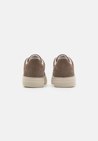 Sapatos de camurça castanhos com um design de cano baixo, solas de borracha bege e backs arredondados. Apresentam costuras subtis e uma textura suave.