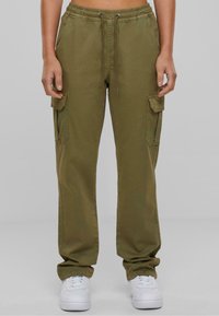Olivgrüne Cargo-Hosen mit einem verstellbaren Bund, Seiten- und Cargo-Taschen sowie einer lockeren Passform, kombiniert mit weißen Sneakers.