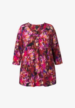 Kukkakuvioinen tunikapaita, jossa on kolme neljännestä hihaa ja kirkkaan pinkkejä, purppuran- ja punaisen sävyisiä kukkia mustalla pohjalla. V-kaula-aukko.