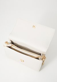 Bolsa de mão em pele branca com um acabamento texturizado, ferragens em dourado, bolso com fecho éclair e uma alça em corrente. A aba possui um detalhe quadrado em dourado.