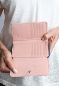 Rosa Lederbrieftasche mit glatter Textur, ausgestattet mit mehreren Kartenfächern, einem Druckverschluss und geprägtem Schriftzug im Inneren.