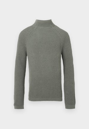 Ribbestrikket genser i lys grønn med høy krage, lange ermer og en tettsittende design. Teksturen er myk og litt elastisk.