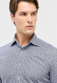 Witte overhemd met een marineblauw bladerenpatroon, voorzien van een klassieke kraag en een gladde textuur, geschikt voor casual of semi-formele gelegenheden.