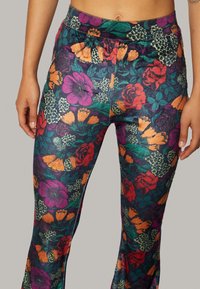 Flared leggings met een kleurrijk bloemenpatroon, in tinten paars, oranje en rood op een donkere achtergrond, gemaakt van rekbaar materiaal.
