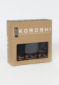 Paquete de tres calzoncillos para hombre en una caja de cartón. Incluye diseños en negro, gris y con patrones, todos con acentos naranjas y logotipos.
