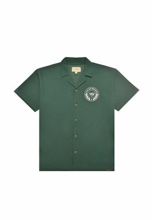 Camicia verde a maniche corte con bottoni e colletto, con logo circolare bianco sul petto a sinistra con la scritta "PAS DE MONACO 911 CLUB."
