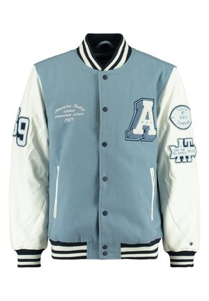 Jasnoniebieska i biała kurtka varsity z prążkowanym kołnierzem i mankietami, ozdobiona naszywkami, w tym dużą literą „A”, numerem „89” oraz emblematami mistrzostw.