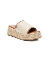 Sandalia deslizante de tela beige tejida con un diseño texturizado, detalles en cuero marrón y una suela de cuña de yute trenzado. Con punta y talón abiertos.