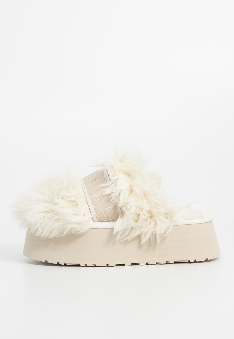 Platformowe sandały z puszystą, off-white futrzaną cholewką, beżowym paskiem i grubą kremową podeszwą. Miękka tekstura i casualowy design.