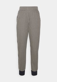 Joggers à carreaux avec une taille élastique et des poignets. Présentent un motif pied-de-poule noir et crème, fabriqués dans un tissu texturé.
