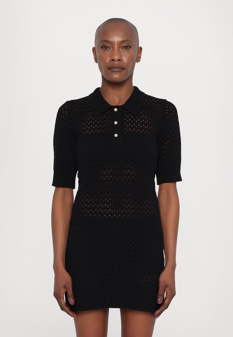 Schwarzes Strickkleid mit Polokragen, kurzen Ärmeln und Knopfdetails. Der Stoff hat ein strukturiertes offenes Muster.