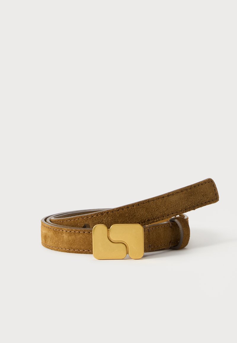 Une ceinture en daim marron enroulée, aux bords surpiqués et dotée d’une grande boucle dorée, sur un fond blanc uni.