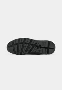 Suela de zapato de goma negra con un patrón de relieve texturizado para mayor agarre, con un surco central y el logo de la marca embosado en la zona del talón.