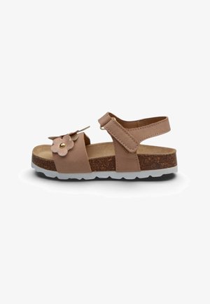 Sandalo beige per bambini con cinturino alla caviglia regolabile, suola in sughero, battistrada bianco e fiore decorativo sulla cinghia anteriore.