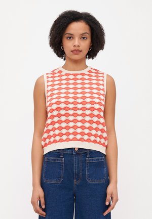 Heklet ermeløs topp med et geometrisk mønster i korall og krem, med ribbestrikket hals og kant. Kombinert med høy midje denimjeans.