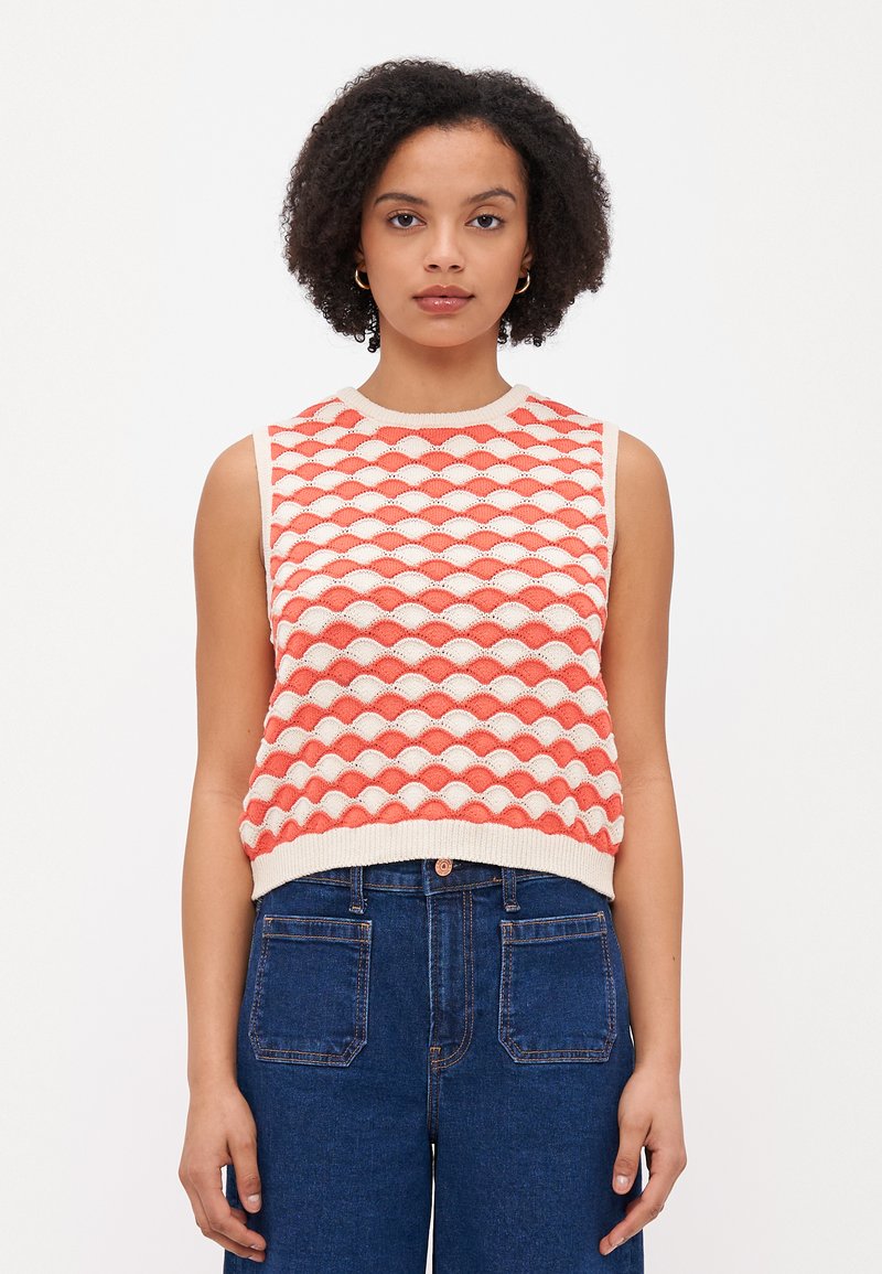 Débardeur en tricot sans manches avec un motif géométrique en corail et crème, avec un col et un ourlet côtelés. Assorti à un jean en denim taille haute.