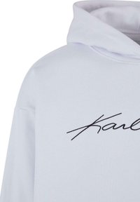 Sudadera blanca con un logotipo bordado en negro en la parte frontal. Está hecha de una tela suave y texturizada con un corte relajado y capucha con cordón.