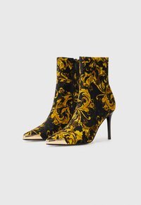 Zwarte enkellaarsjes met een gouden bloemenpatroon, spitse neus, gouden accent op de neus en een slanke stiletto-hak met een zijrits.