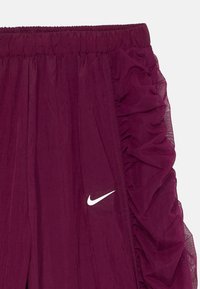 Μαρέν παντελόνι Nike με φάσα πλέγματος στο πλάι, ελαστική μέση και λευκή λογότυπο στην κάτω μπροστινή πλευρά. Λείο υφασματικό τελείωμα.