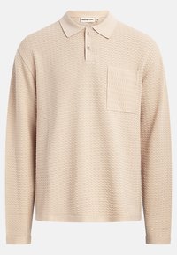 Beige long-sleeve polo shirt featuring a textured wave pattern, a classic collar, three buttons, and a left chest pocket.