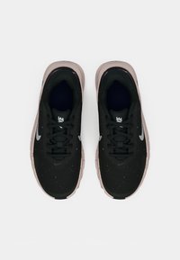 Fekete sportcipők textúrált hálós felsőrésszel, világos rózsaszín talppal és fehér logóval. Lapított fűzőkkel és párnázott bokarésszel rendelkezik.