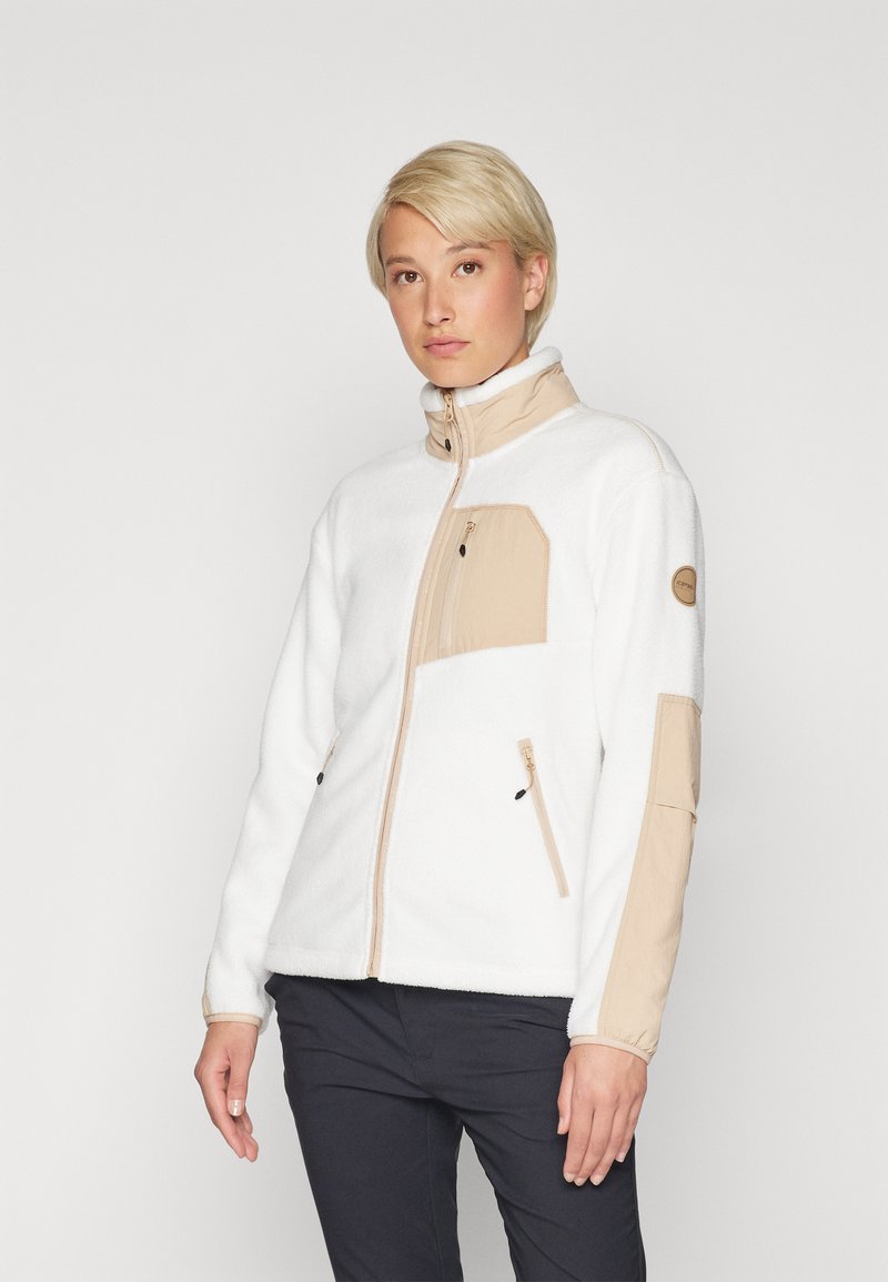 Giacca in pile bianca con pannelli beige sulle spalle e sul petto, colletto alto, tasche con zip e polsini elasticizzati. Texture liscia, design casual.