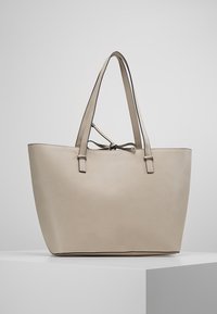 Beige læder tote taske med lange håndtag, struktureret form og et minimalistisk design. Har en knyttet lukning og diskrete syninger.