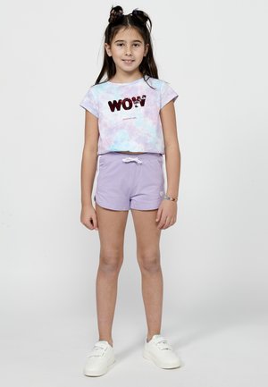 Lila korte broek en pastel tie-dye t-shirt met de tekst "WOW" in rode pailletten. Het t-shirt heeft kapmouwen, de korte broek heeft een verstelbare taille met koord en een hartlogo.