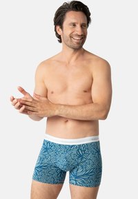 Caleçons boxers à motifs bleus avec une ceinture élastique blanche, ornés de motifs floraux et dotés d'une texture de tissu lisse.