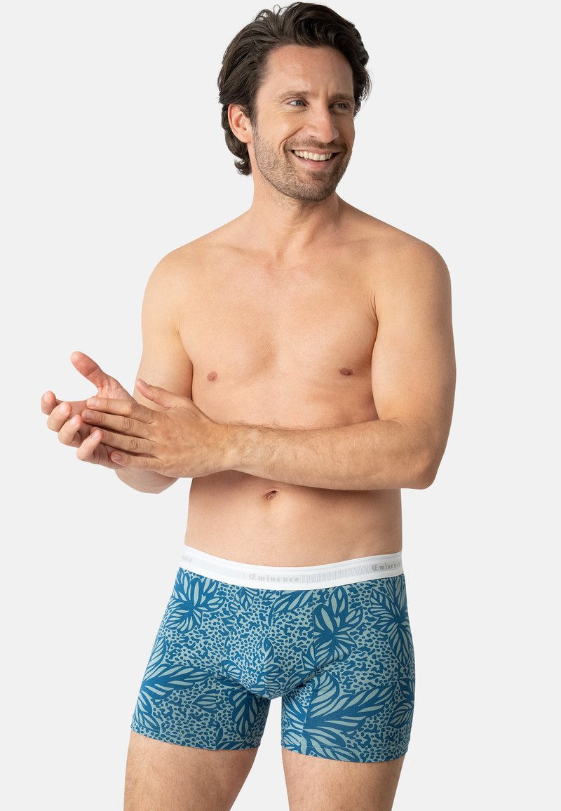 Caleçons boxers à motifs bleus avec une ceinture élastique blanche, ornés de motifs floraux et dotés d'une texture de tissu lisse.