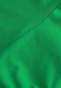 Green fabric featuring a smooth texture with an even finish, displaying two overlapping sections of similar shades.