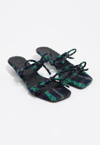Sandalias planas multicolores y texturizadas con rayas en azul marino, verde y naranja, que presentan dos lazos y un diseño de punta cuadrada. Suelas negras.