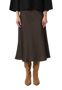 Brown satin midi skirt with a flowing silhouette, paired with fitted beige suede knee-high boots featuring pointed toes.