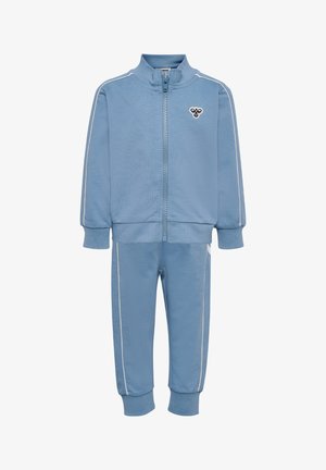 Lyseblåt træningssæt lavet af blødt stof, der består af en lynlåstrøje med opretstående krave og hvide sidestriber, kombineret med matchende bukser.