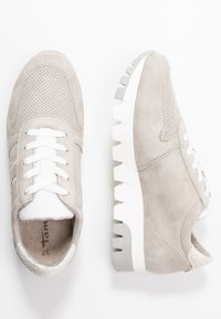 Vaaleanharmaat mokkasneakerit valkoisilla nauhoilla, rei'itetty kärki ja jykevä valkoinen pohja, jossa syvät urat, esiteltynä ylhäältä ja sivulta.