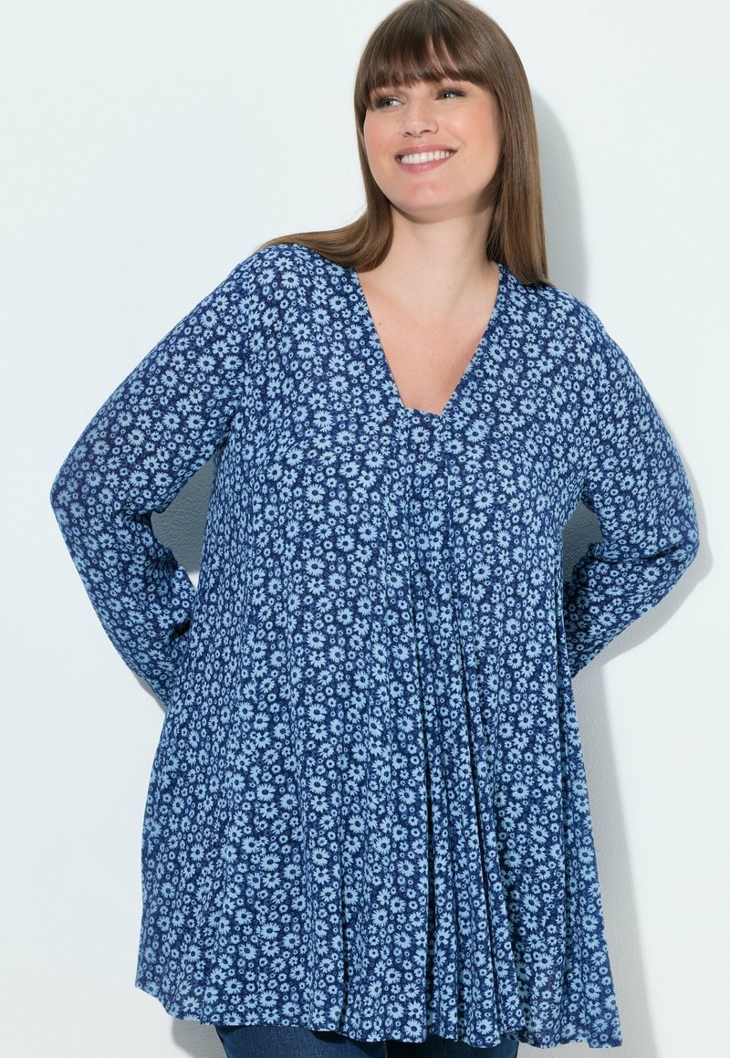 Niebieska kwiecista bluzka z dekoltem w serek i długimi rękawami. Charakteryzuje się luźnym krojem z plisami i powtarzającym się wzorem kwiatowym w jasnoniebieskim kolorze.