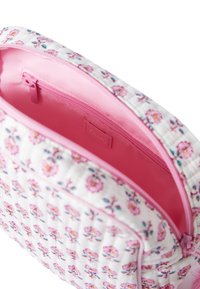 Borsa cosmetica trapuntata bianca con motivo floreale, interno rosa e chiusura con zip. Comprende una piccola tasca interna per l'organizzazione.