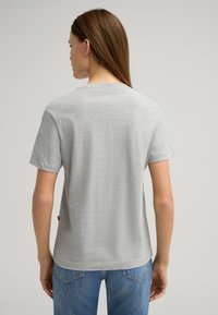 Grijze korte mouwen t-shirt van zacht stof, met een klassieke ronde hals en een label aan de zijkant. Rechte snit, relaxte pasvorm.