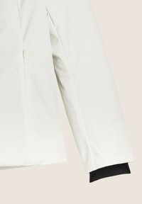 Giacca impermeabile bianca con interno foderato, dotata di una tasca con zip e polsini neri elasticizzati alle aperture delle maniche.