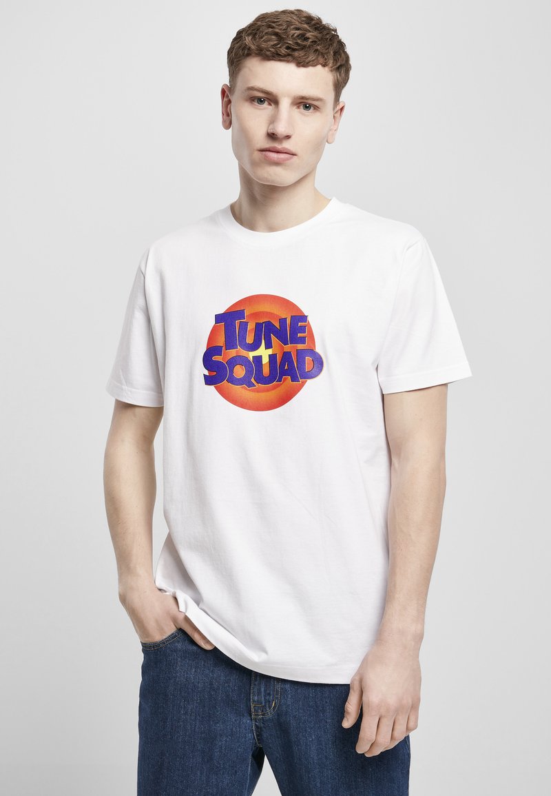Hvit bomullst-skjorte med et rundt grafisk motiv i oransje og blått med teksten "TUNE SQUAD" i fet skrift. Korte ermer og en avslappet passform.