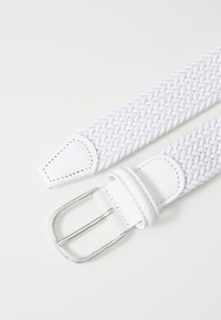 Cinturón tejido blanco con punta de cuero suave y hebilla de metal plateado. Patrón texturizado a lo largo de toda la longitud del cinturón.