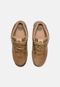 Braune Lederwanderschuhe mit gelben und burgunderfarbenen Schnürsenkeln, ausgestattet mit einem gepolsterten Knöchelbereich und einer strukturierten Außensohle für besseren Halt.