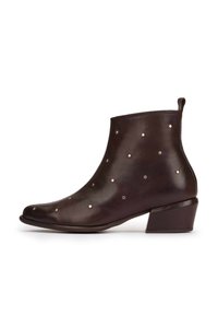 Bruine leren enkelboot met een spitse neus en een lage blokhak, versierd met kleine metalen studs die gelijkmatig over het oppervlak zijn verdeeld.